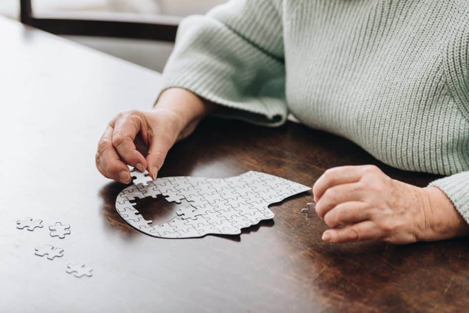 senior hands building a mental health head puzzle